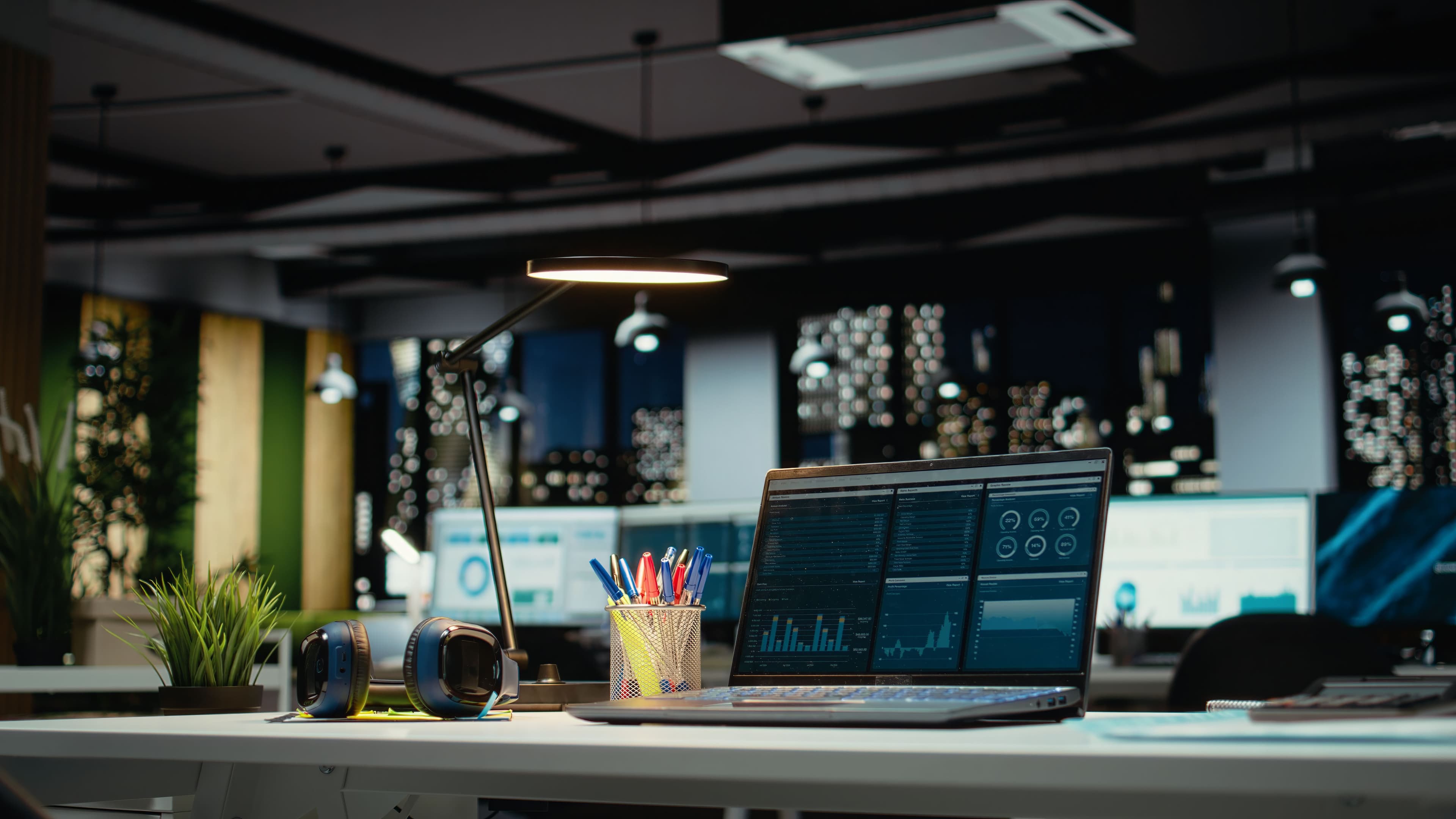 Laptop displaying data analytics on a modern office desk with various desk supplies.